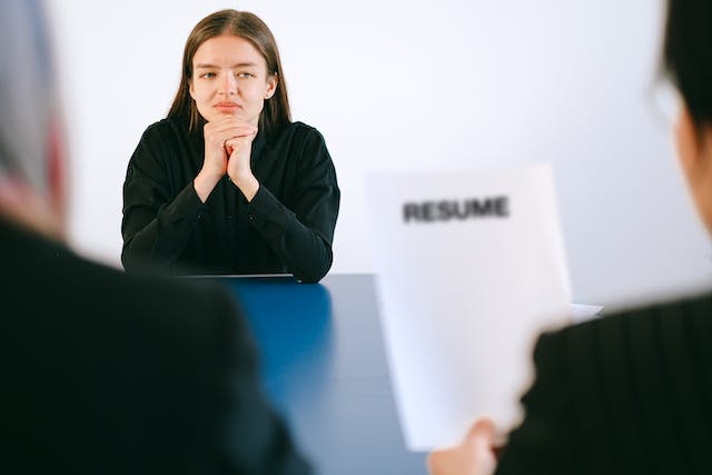 job applicant staring at interviewers reviewing her resume